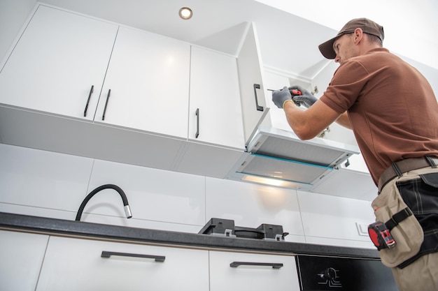 پیمانکار در حال نصب کابینت آشپزخانه با دقت و ابزارهای حرفهای